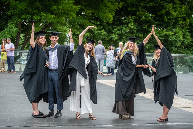 Students at graduation 2022 spell out the letters UCA with their hands