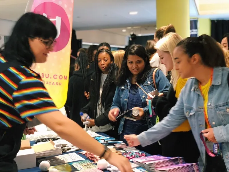 A group of new students pick up information and freebies from a stall at UCASU Freshers Week