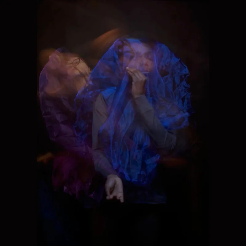 A distorted long exposure photograph of a girl against a black background