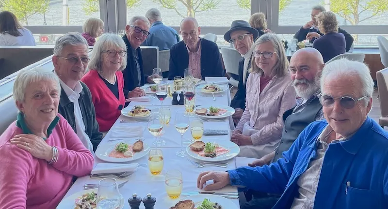 A group of UCA alumni sitting around a table with food and drinks
