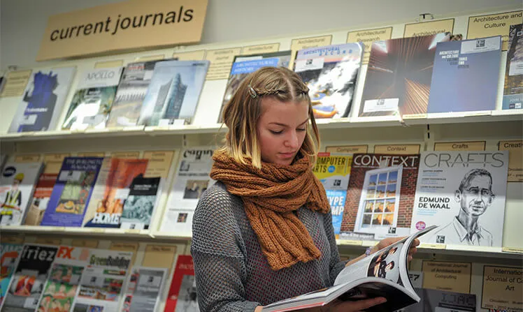 A female student reading a book in the UCA Canterbury library