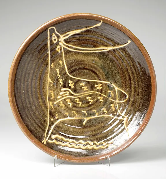 Large slipware dish, dark brown with a white stag in the centre. Sam Haile, c.1945-46. © Estate of the artist / Crafts Study Centre (P.80.2)