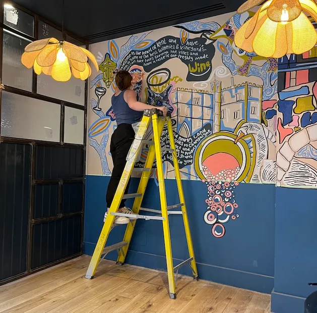 Bri Chartrand at work on one of her murals, stood on a ladder