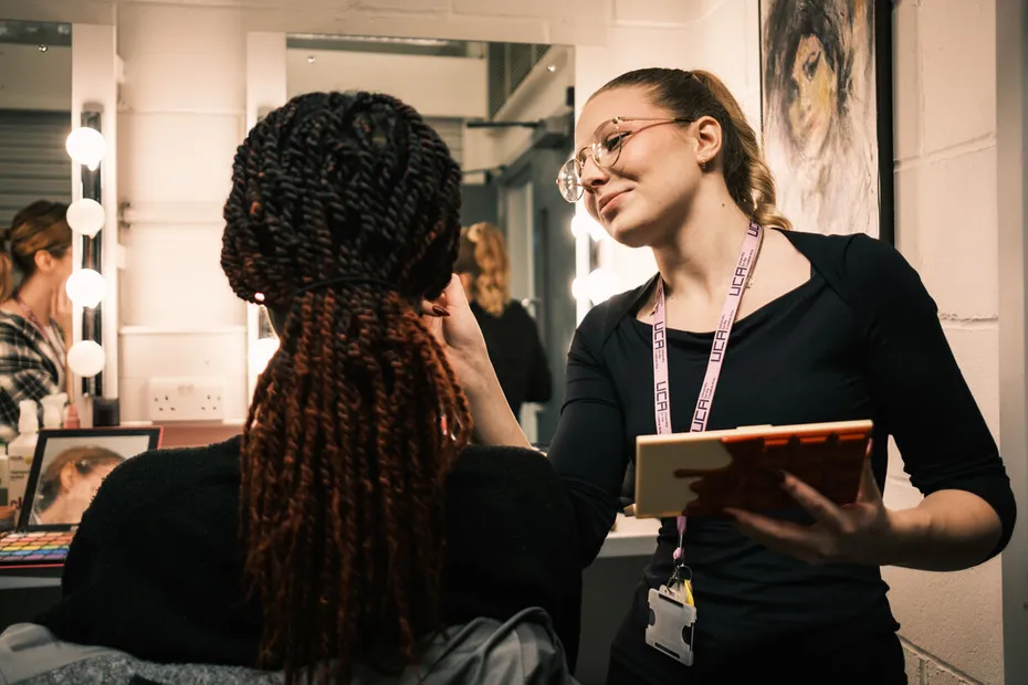 Student applying make-up to a model