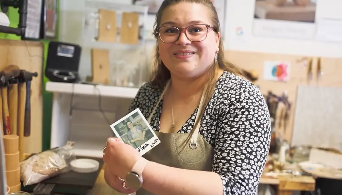 Abigail Marsh holding a photo of herself in a jewellery studio