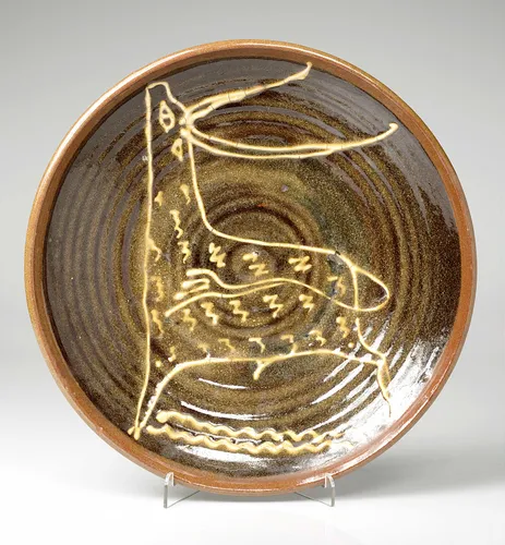 Large slipware dish, dark brown with a white stag in the centre. Sam Haile, c.1945-46. © Estate of the artist / Crafts Study Centre (P.80.2)