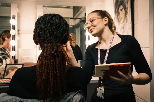 Student applying make-up to a model