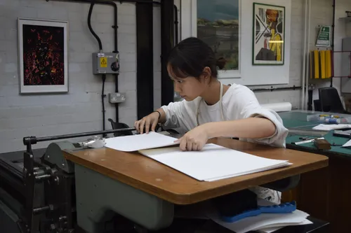 A student focusing on their work in preparation for printing