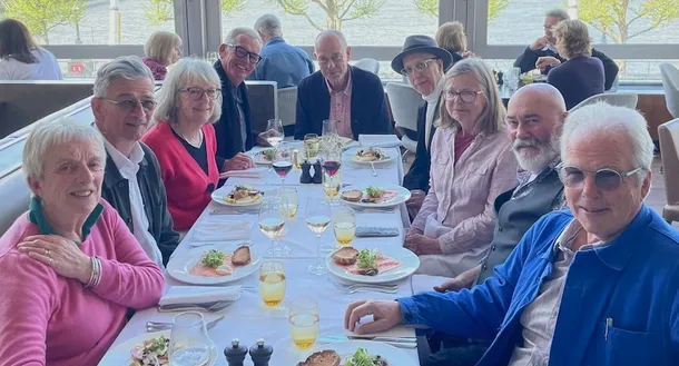 A group of UCA alumni sitting around a table with food and drinks