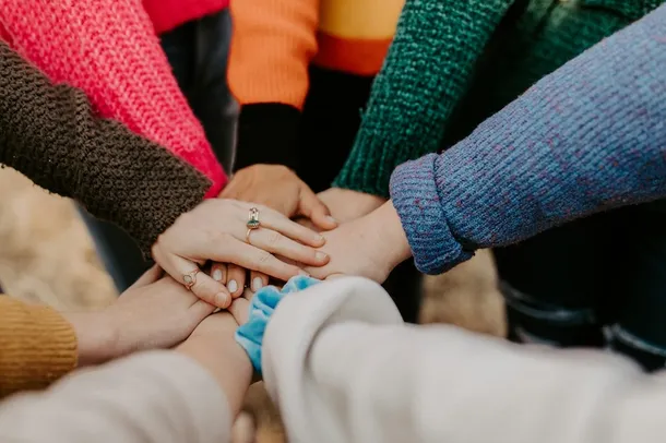 Several hands connected together. Picture by Hannah Busing at Unsplash