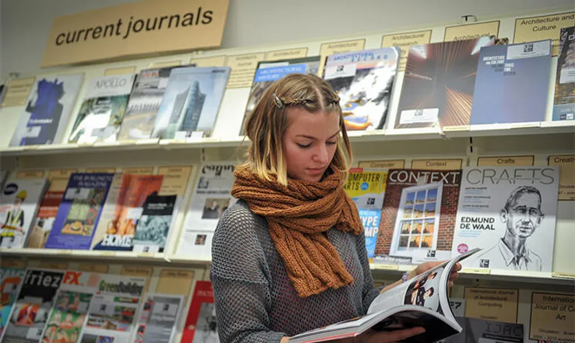 A female student reading a book in the UCA Canterbury library