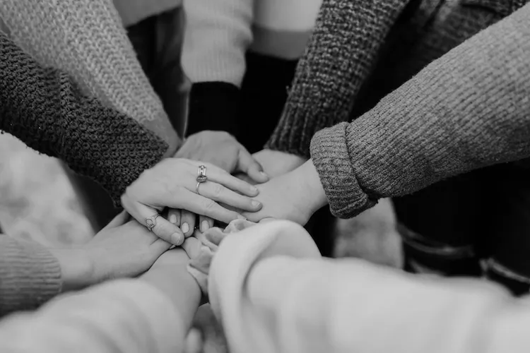 Several hands connected together. Picture by Hannah Busing at Unsplash